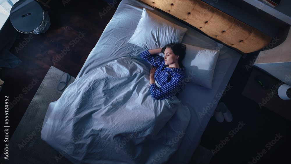 Top View of Beautiful Young Woman Sleeping Cozily on a Bed in Her Bedroom at Night. Comfortable Apar