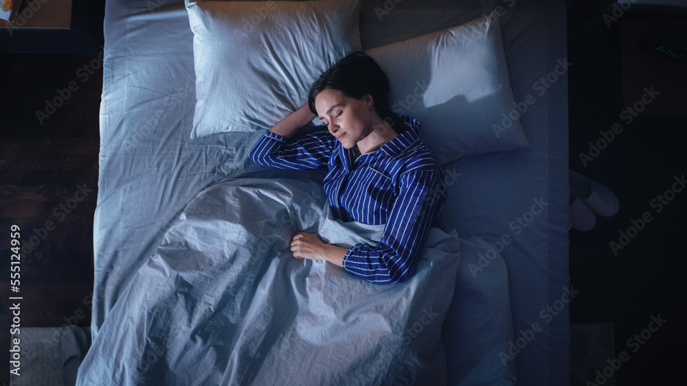 Top View of Beautiful Young Woman Sleeping Cozily on a Bed in Her Bedroom at Night. Comfortable Apar