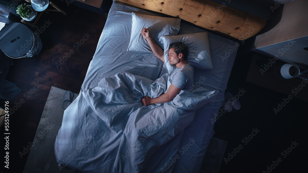 Top View Apartment Bedroom: Handsome Young Man Sleeping Cozily on a Bed in His Bedroom at Night. Com