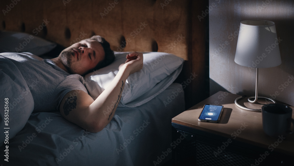 Caucasian Man Sleeps through Smartphone Alarm Clock Showing Eight in the Morning. Tired Person Overs