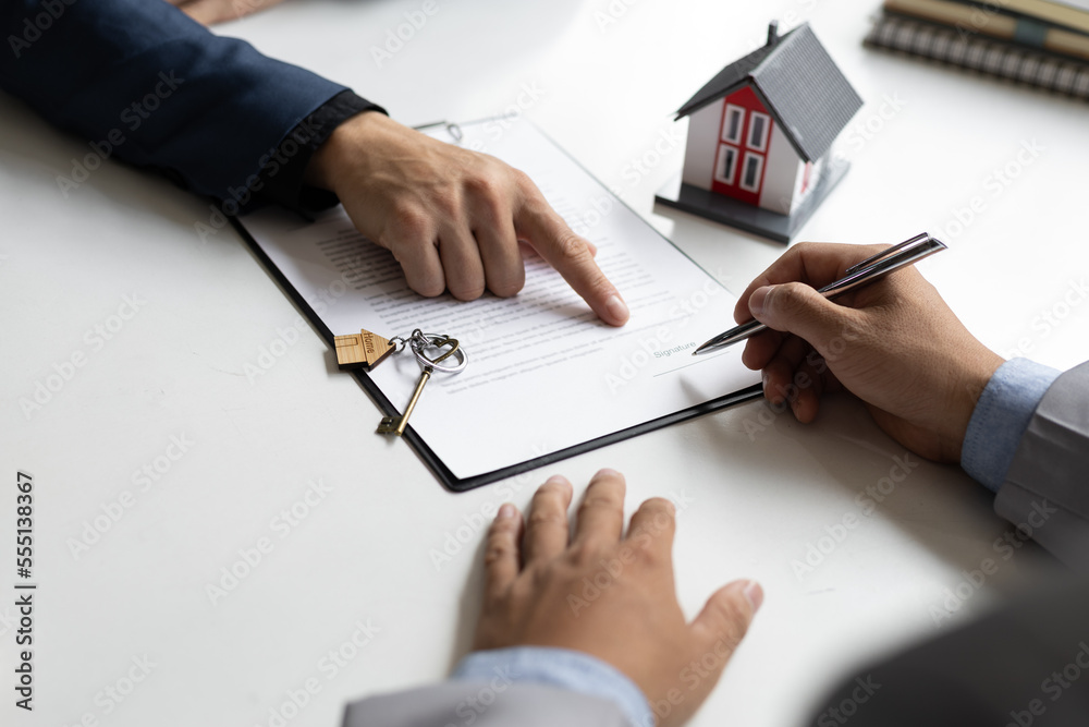 Businessmen and real estate agents sign contracts to legally sell homes.