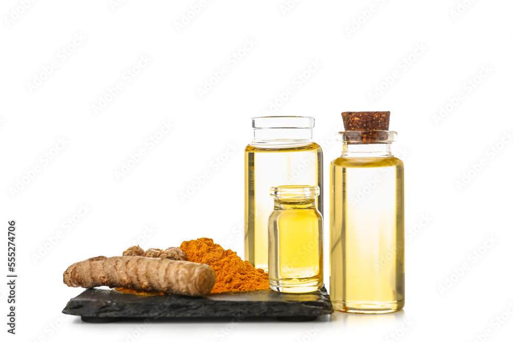 Bottles of essential turmeric oil, powder and root on white background