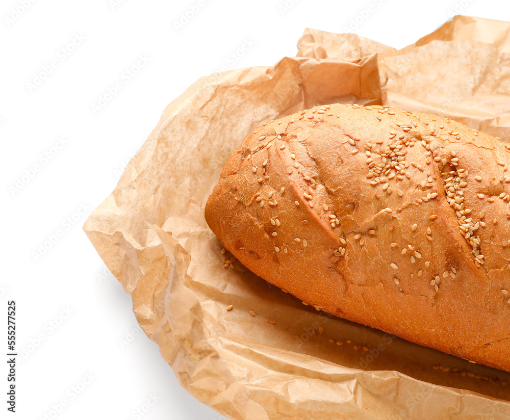 Baking paper with loaf of fresh bread on white background, closeup