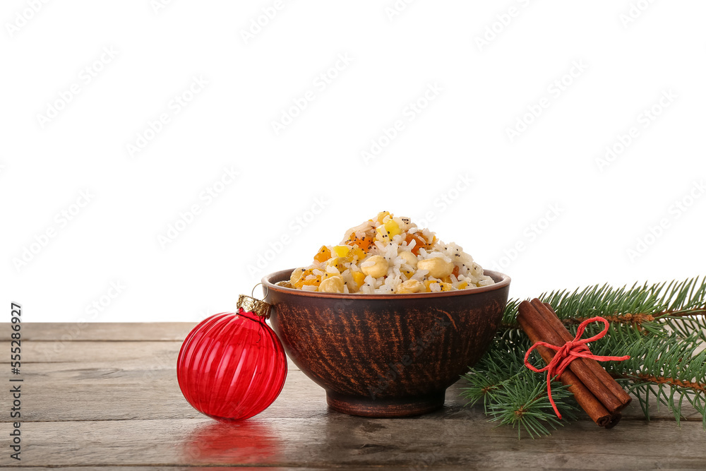 Bowl of rice Kutya, Christmas ball, fir branches and cinnamon on table against white background