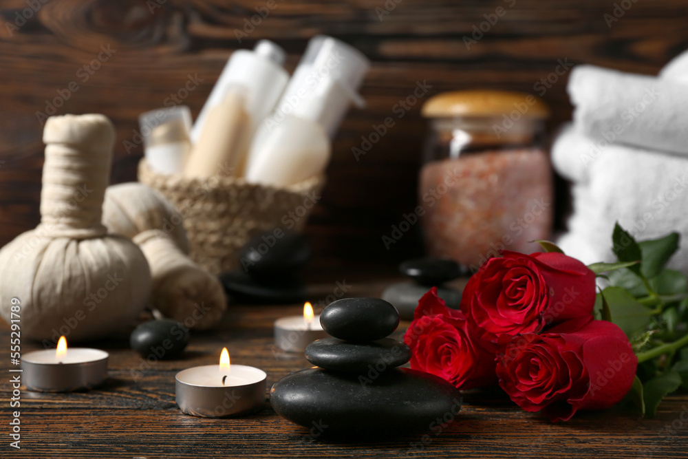 Beautiful spa composition for Valentines Day with stones, candles and rose flowers on wooden backgr