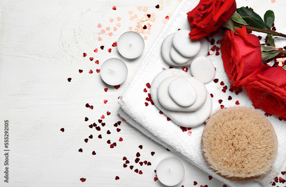 Beautiful spa composition for Valentines Day with rose flowers, brush, towel and stones on white wo