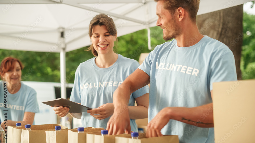 Happy Group of Volunteers Helping in a Local Community Food Bank, Preparing Free Meal Rations to Low