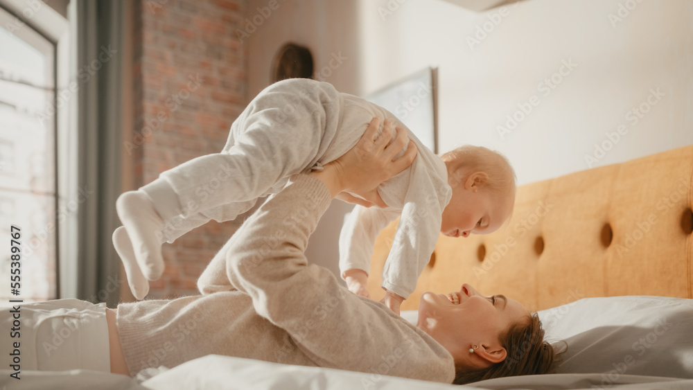 Caring Mother Lying on a Bed, Playing with a Cute Newborn Baby at Home. Mom Bonding with a Toddler, 