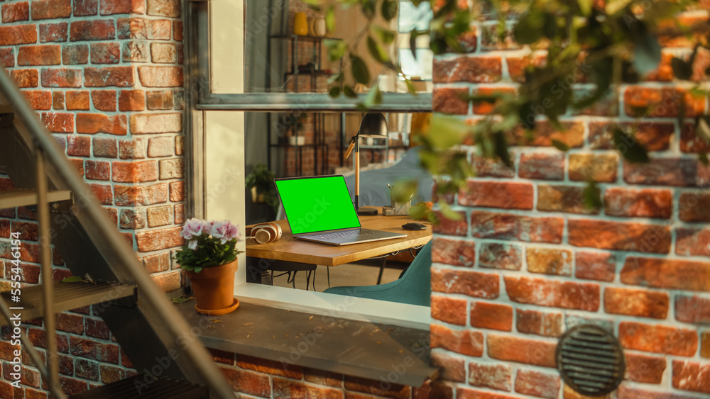 Laptop Computer with Green Screen Mock Up Display Standing on a Table in Stylish Living Room. View f