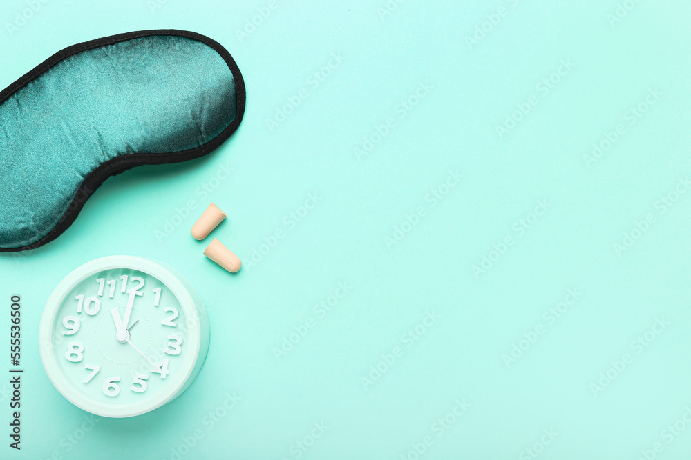 Earplugs, sleeping mask and alarm clock on color background