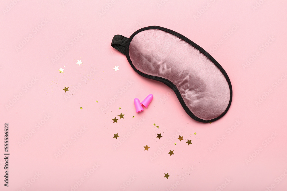 Earplugs and sleeping mask on pink background