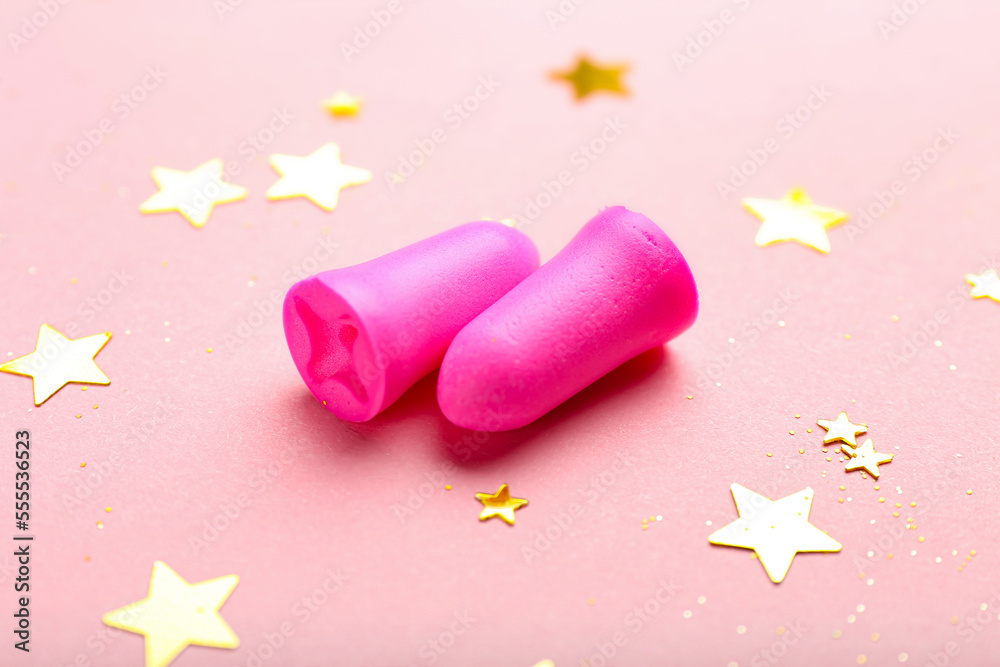 Foam ear plugs and golden sequins on pink background