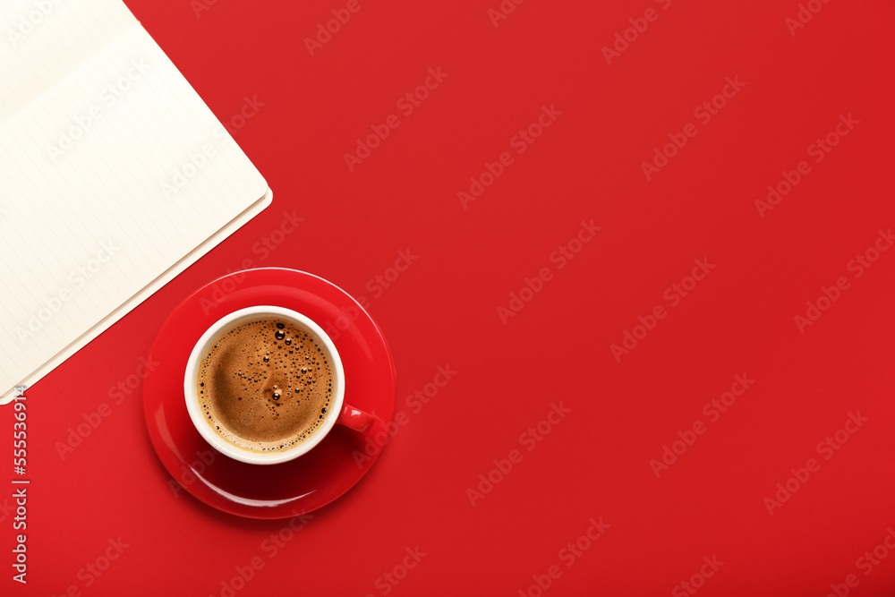 Cup of coffee and notebook on red background