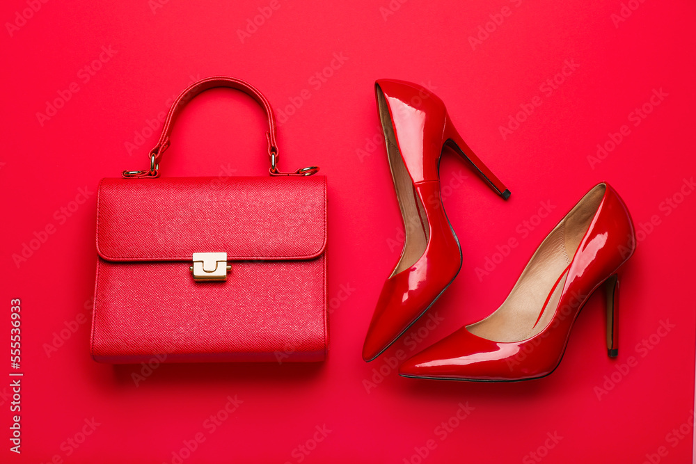 Stylish bag and heels on red background