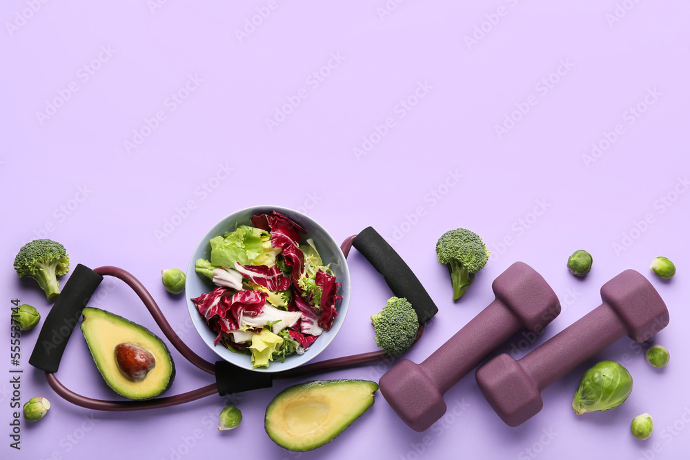 Bowl with vegetable salad, dumbbells and expander on color background