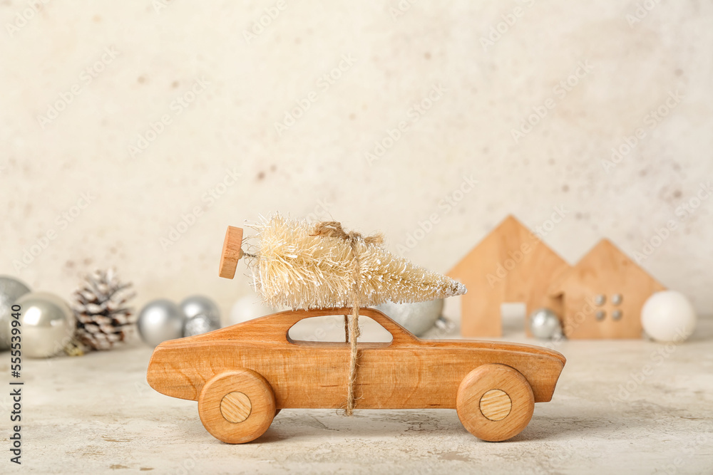 Wooden toy car with Christmas tree on light background