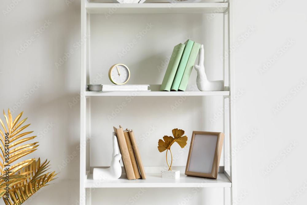 Shelving unit with bookends, frame and alarm clock near light wall