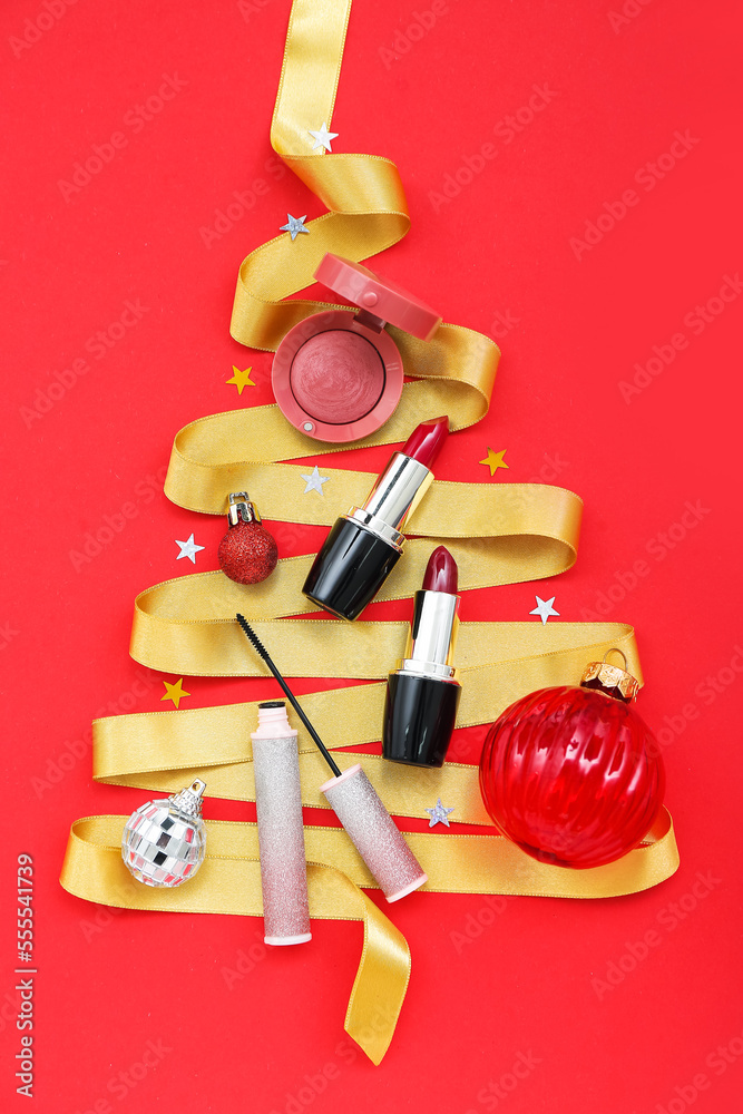 Christmas tree made of decorative cosmetics and ribbon on red background