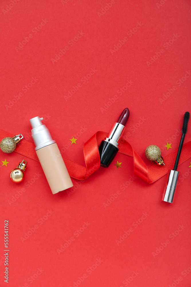 Composition with decorative cosmetics, ribbon and Christmas balls on red background