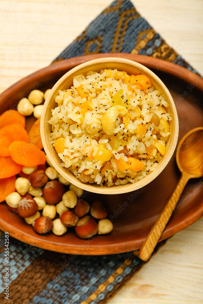 Tray with bowl of rice Kutya, dried apricots and nuts on wooden background