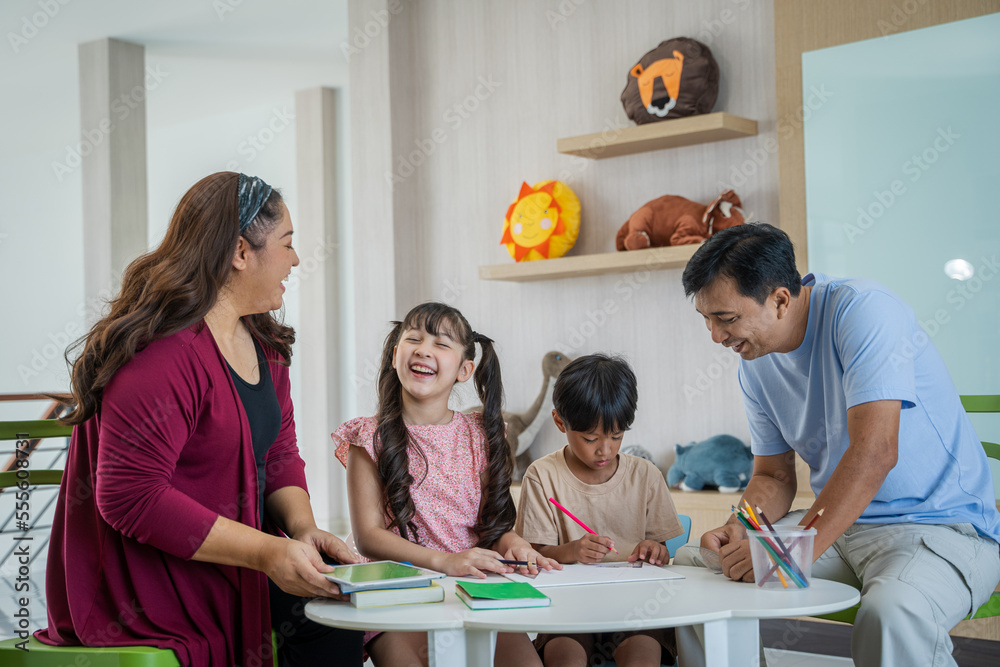 Father teaching children homework in living room.