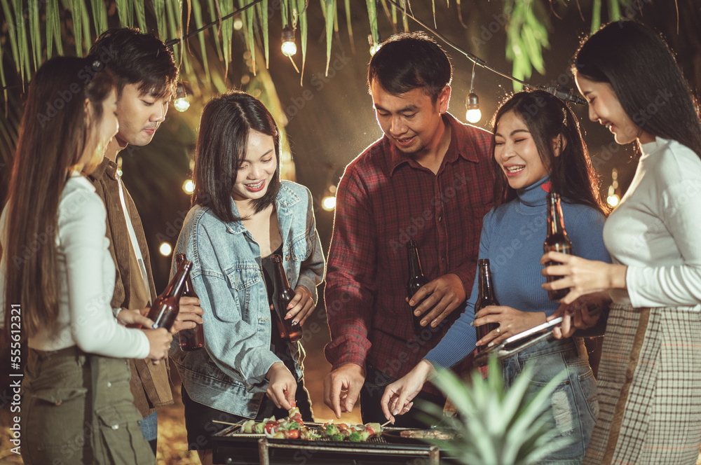 A Group Of Friends Helping Themselves To Food At A Summer Barbecue