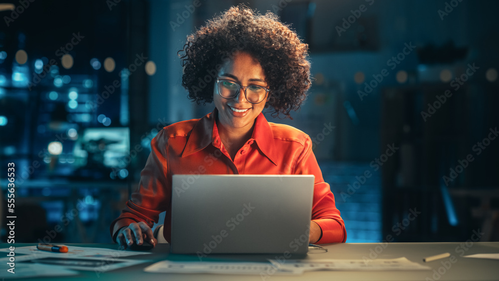 Young Black Female Working on Laptop Computer in Creative Office in the Evening. Happy Multiethnic P