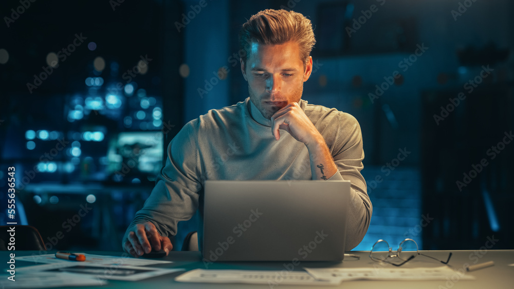 Handsome Man Working on Laptop Computer in a Company Office at Night. Young Specialist Analyzing Rep