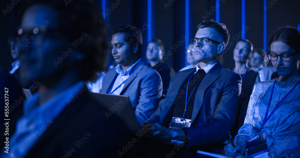 Young Man Sitting in a Crowded Audience at a Business Conference. Corporate Delegate Watching Inspir