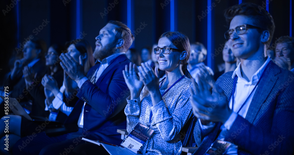 科学会议上，年轻女性坐在拥挤的观众中。代表欢呼和鼓掌