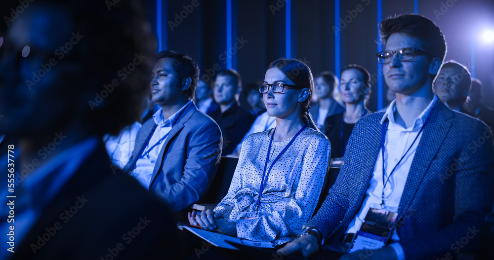 科学会议上，年轻女性坐在拥挤的观众中。代表欢呼和鼓掌