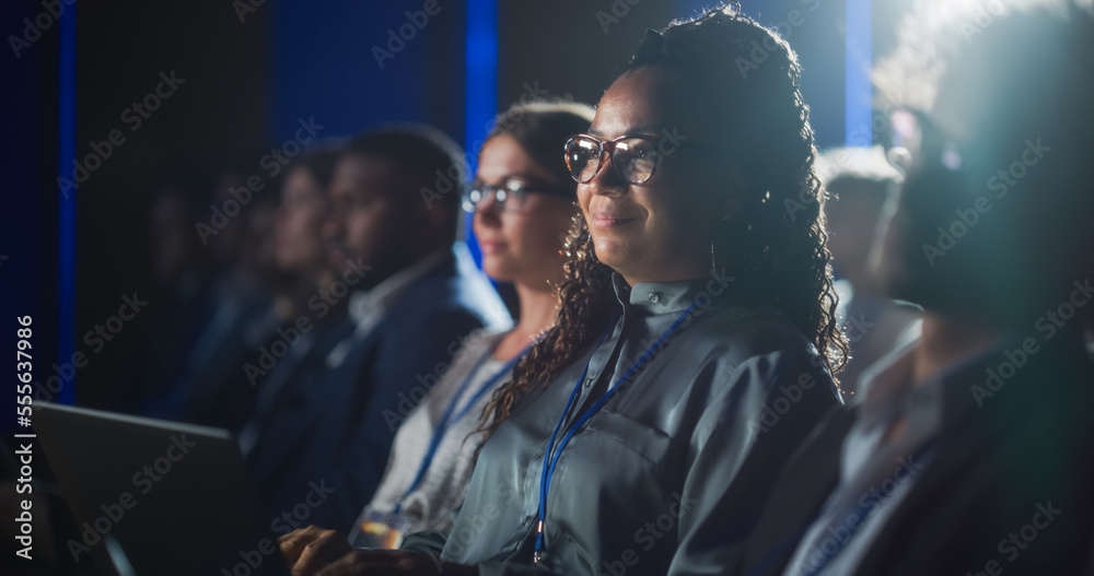 Black Female Sitting in Dark Crowded Auditorium at an International Business Conference. Multiethnic