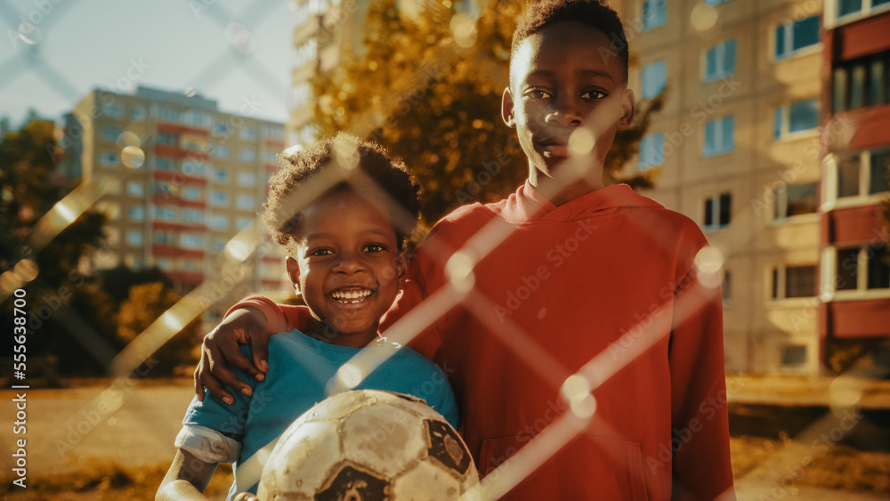 Portrait of Two Young Handsome Black Boys Embracing Each Other while Looking at Camera and Smiling. 