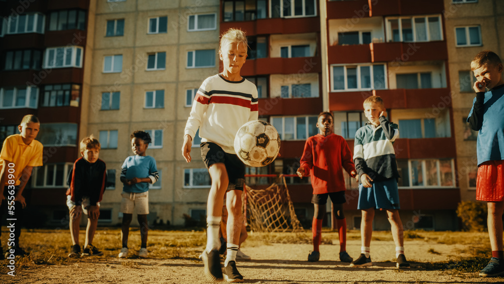 Portrait of a Young Boy Playing Kick-Ups with a Soccer Ball with Friends in a Neighborhood. Happy Mu