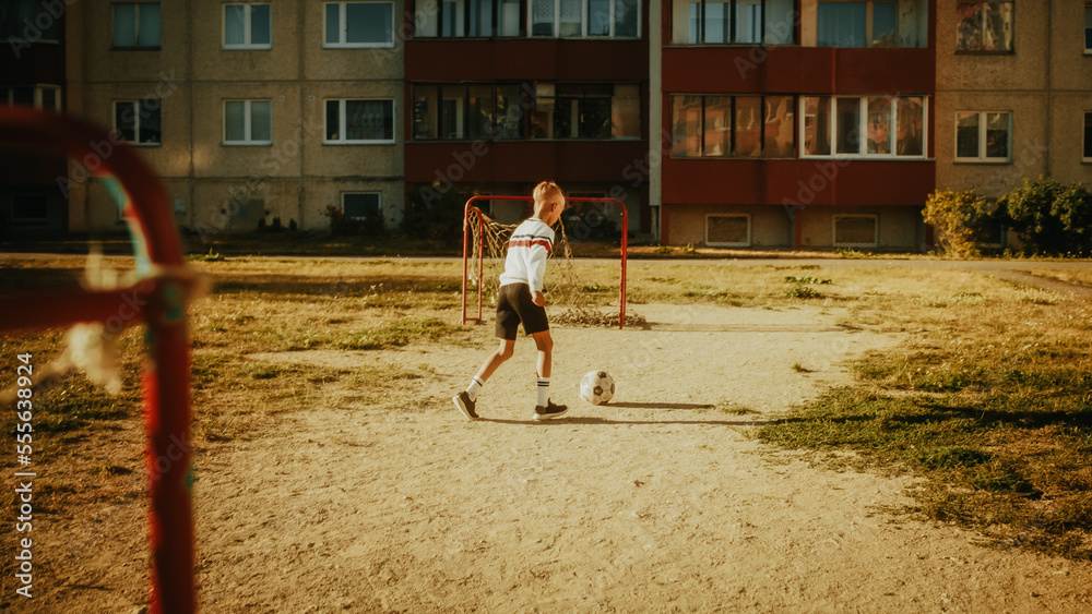 Young Caucasian Kid Playing with Ball in the Neighborhood. Young Boy Practicing Soccer Drills, Doing