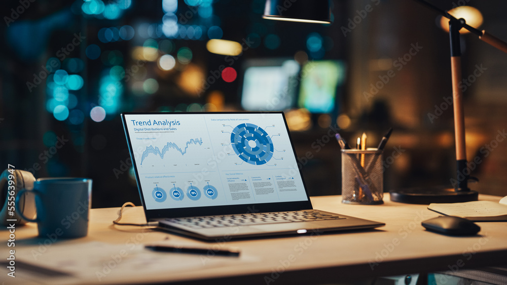 Laptop Standing on a Desk with Sales Statistics and Data Chart Displayed on Screen. Table with Compu