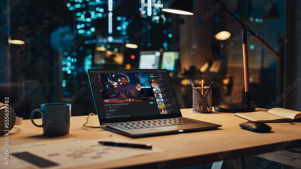 Laptop Standing on a Desk with a Video Streaming Platform Displayed on Screen. Table with Computer, 