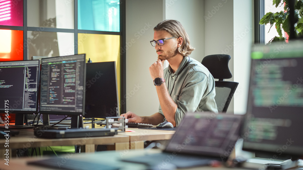 Focused Caucasian Man Coding On Desktop Computer in Stylish Office Space. Male Software Engineer Dev