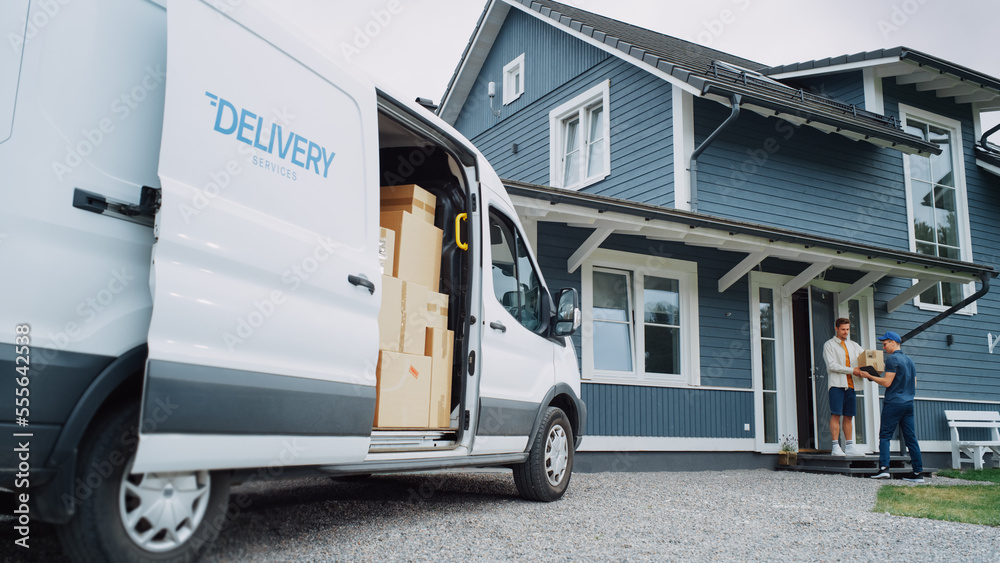 Handsome Young Homeowner Receiving an Awaited Parcel from a Cheerful Courier. Postal Service Worker 