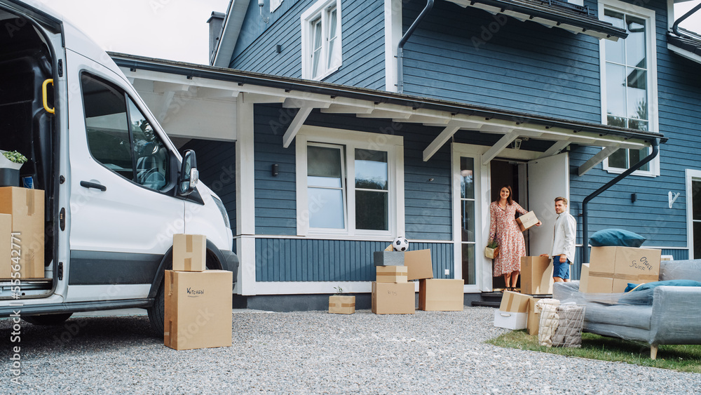 Young Family Moving to Their New Home in Residential Area. Handsome Man Unloading a Cargo Van Full o