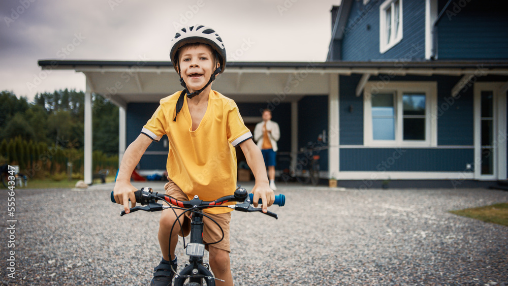 Cheerful Father Teaching His Son to Ride a Bicycle in The Front Yard of Their Beautiful Residential 