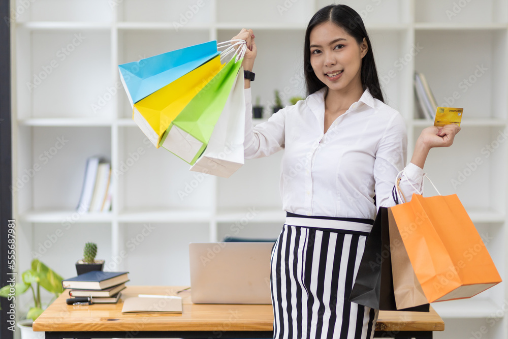 Happy young asian woman holding shopping bag and credit card on vacation.