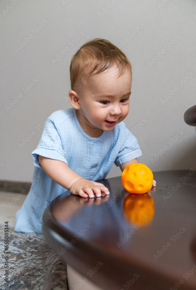 Little boy sitting on stairs and playing with colorful toy. Foyer and living room interior. Home saf