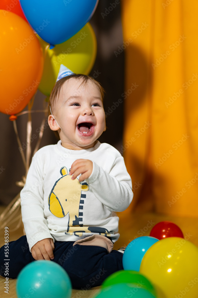 First birthday baby boy party. Smiling baby boy with bunch of colorful balloons. Birthday celebratio