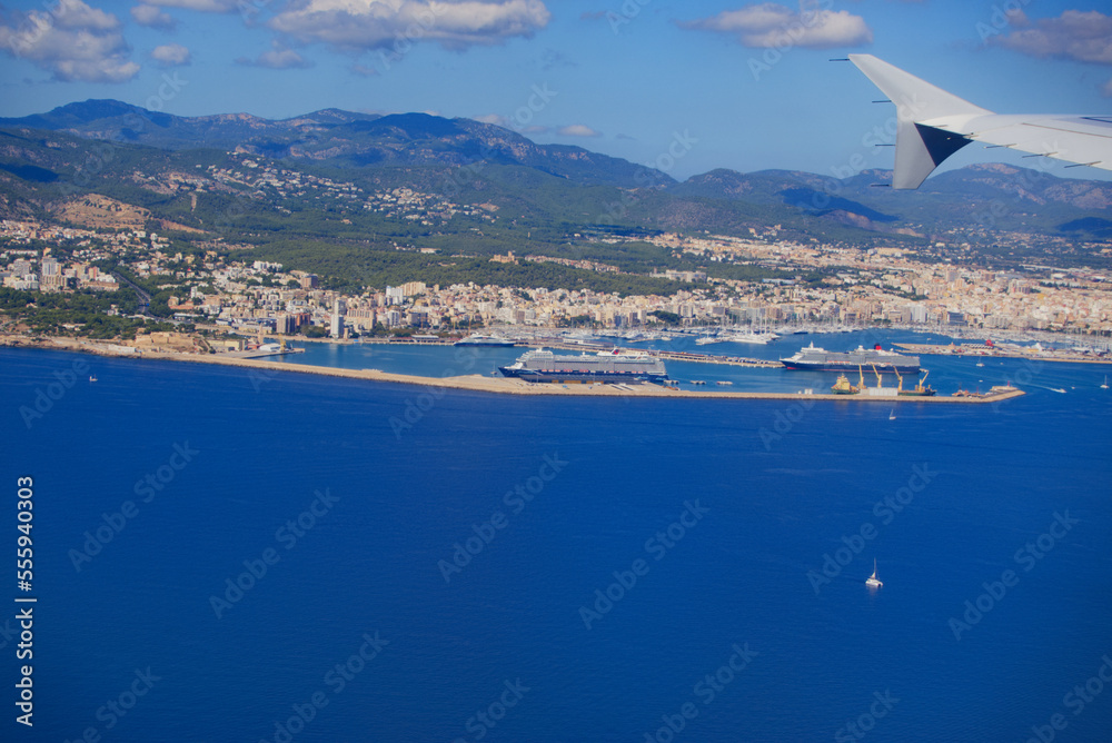 Aerial view of Mallorca Island with coast and ships seen through window of plane on a sunny autumn d