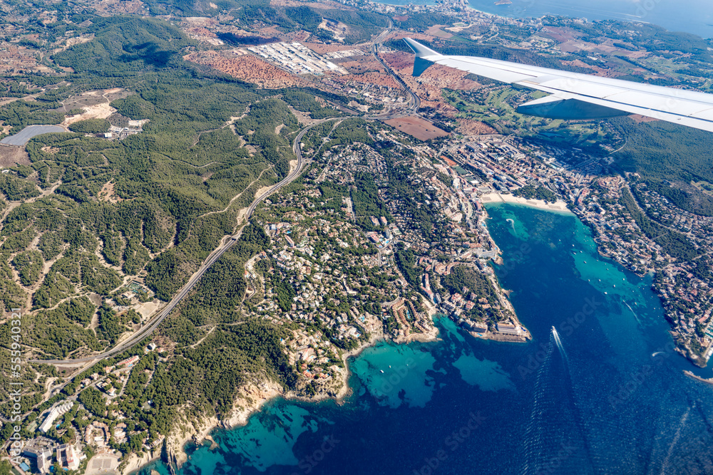 Aerial view of Mallorca Island with coast and ships seen through window of plane on a sunny autumn d