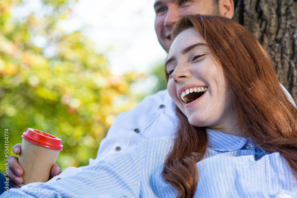 Young couple relaxing with coffee under tree