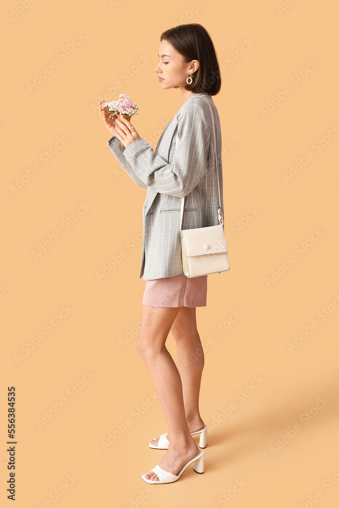 Young beautiful woman holding bouquet of flowers on color background