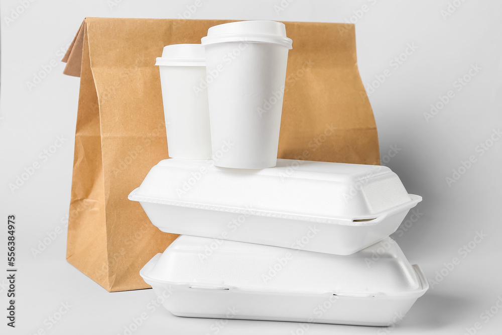 Stack of food containers and paper cups on light background