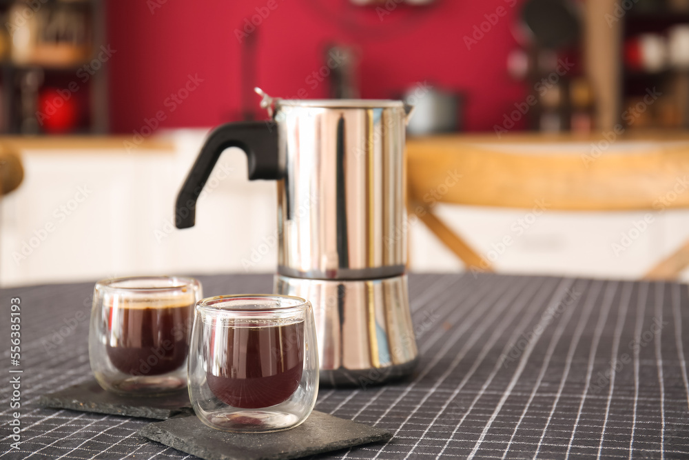 Coffee pot and cups on dining table in stylish kitchen